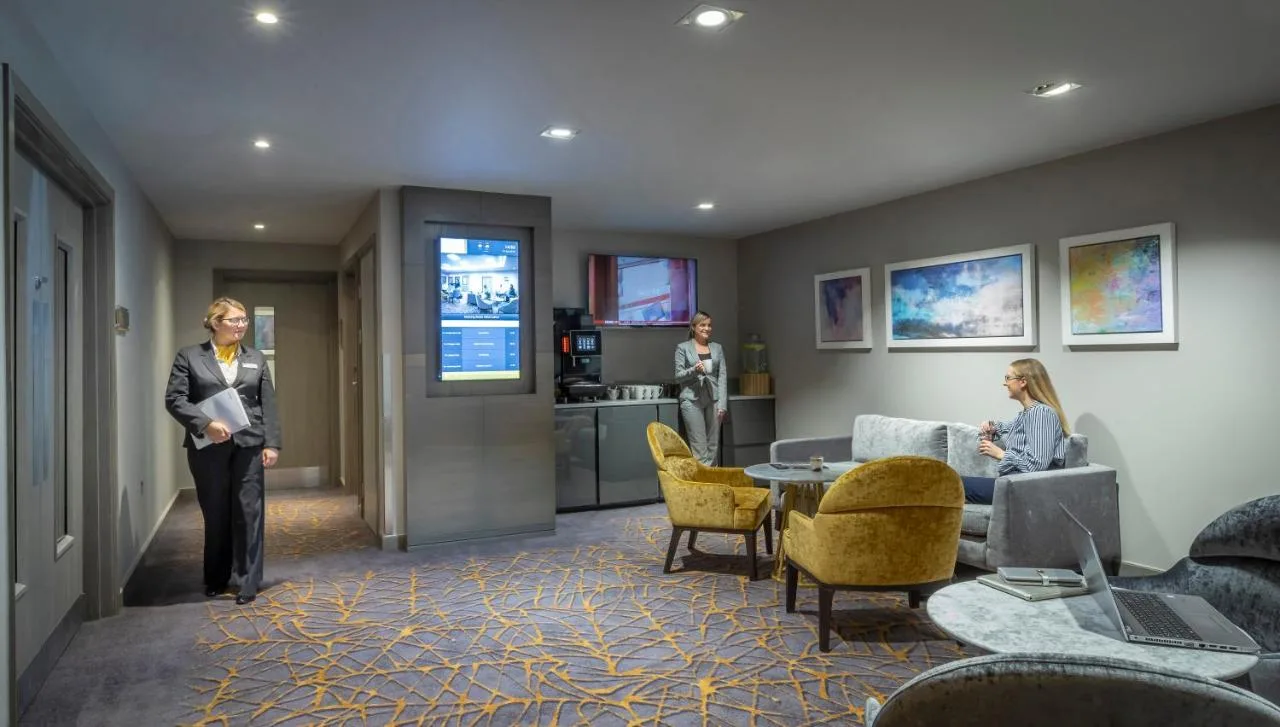 a woman is standing in a lobby with a room at Maldron Hotel Newcastle in Newcastle upon Tyne