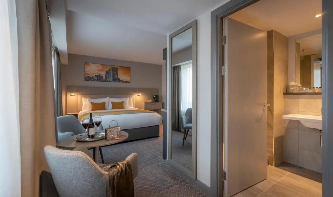 a hotel room with a bed and a table and a mirror at Maldron Hotel Newcastle in Newcastle upon Tyne